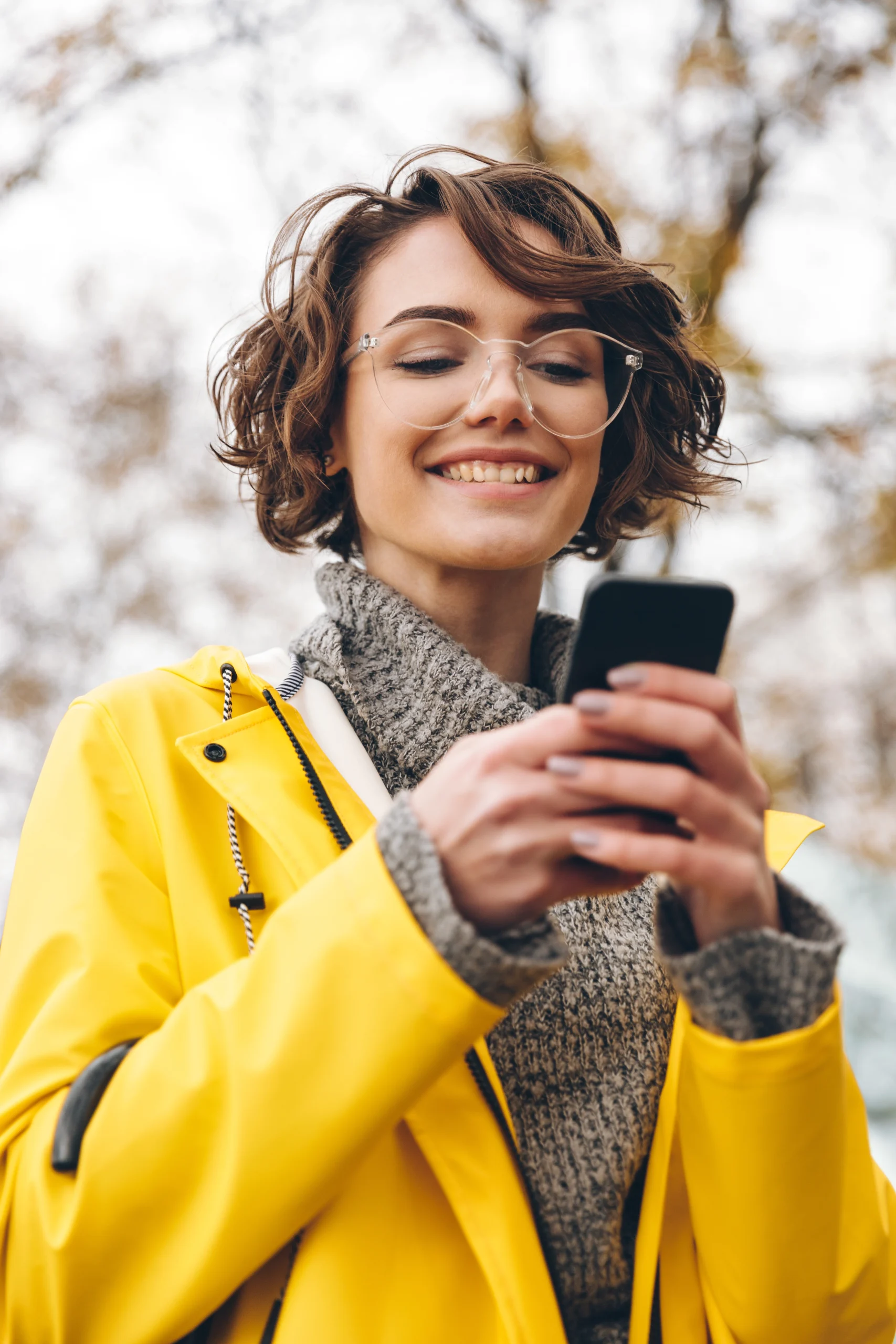 Mujer joven revisando su móvil con gesto relajado, representando el uso cotidiano de la app Emotinet para apoyo emocional personalizado